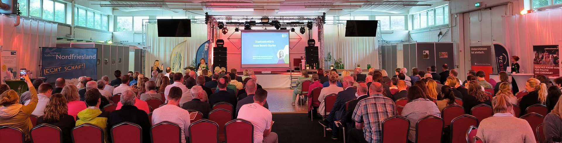 Voller Saal mit Blick auf eine Bühne