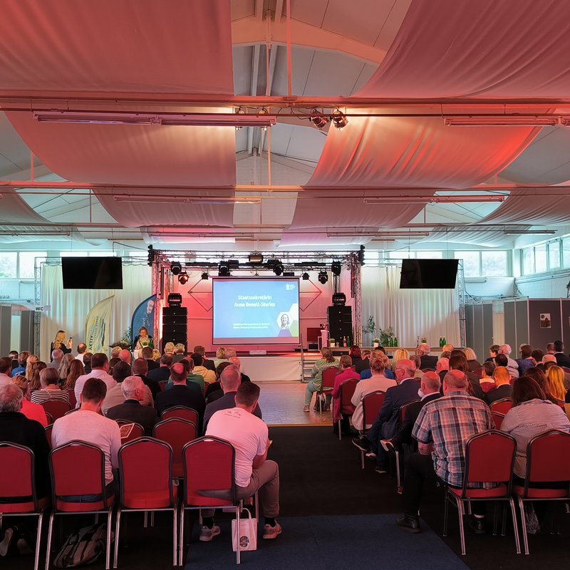 Voller Saal mit Blick auf eine Bühne
